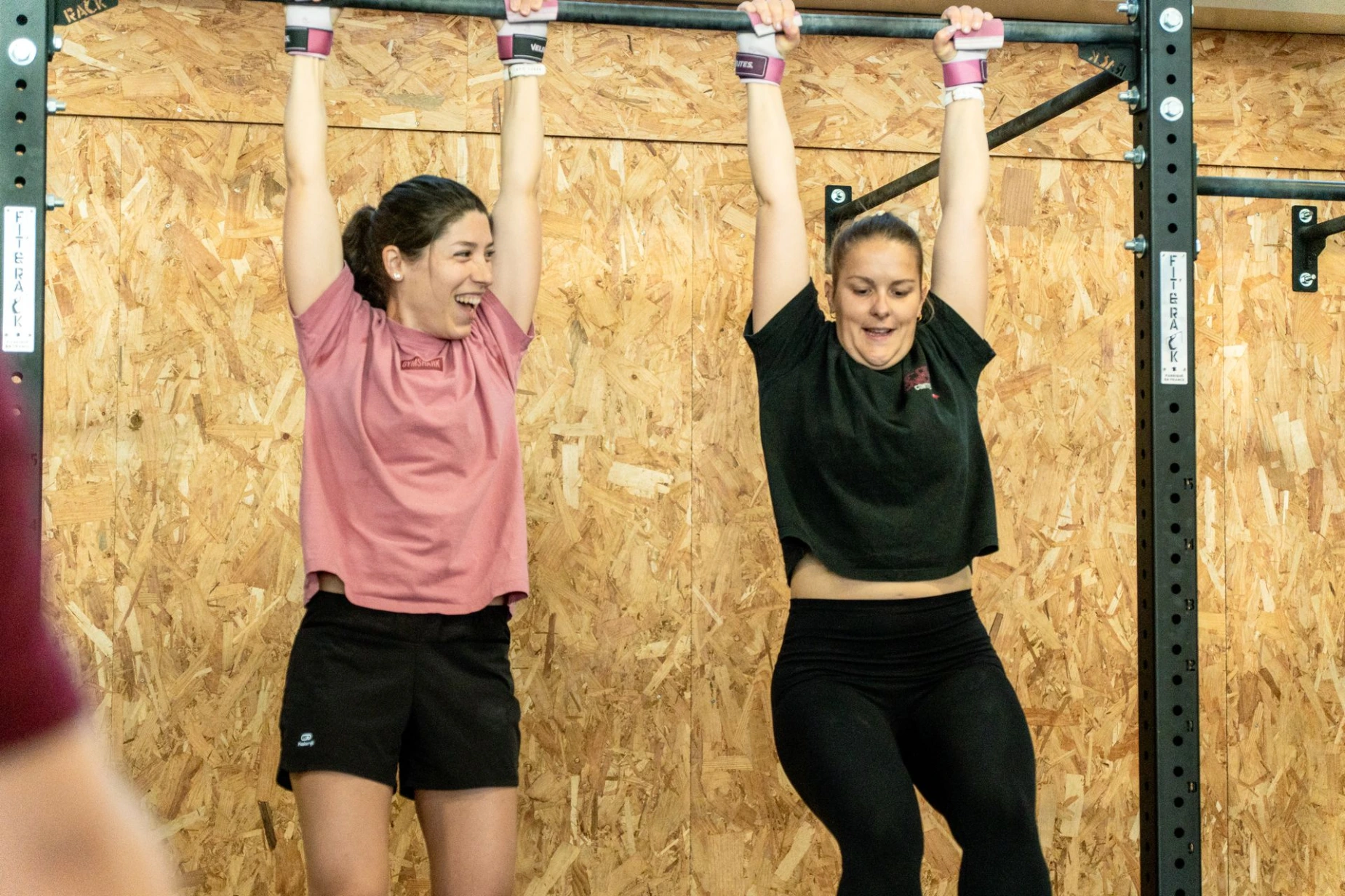 Deux membres souriantes à la barre de traction chez CrossFit Ocelot